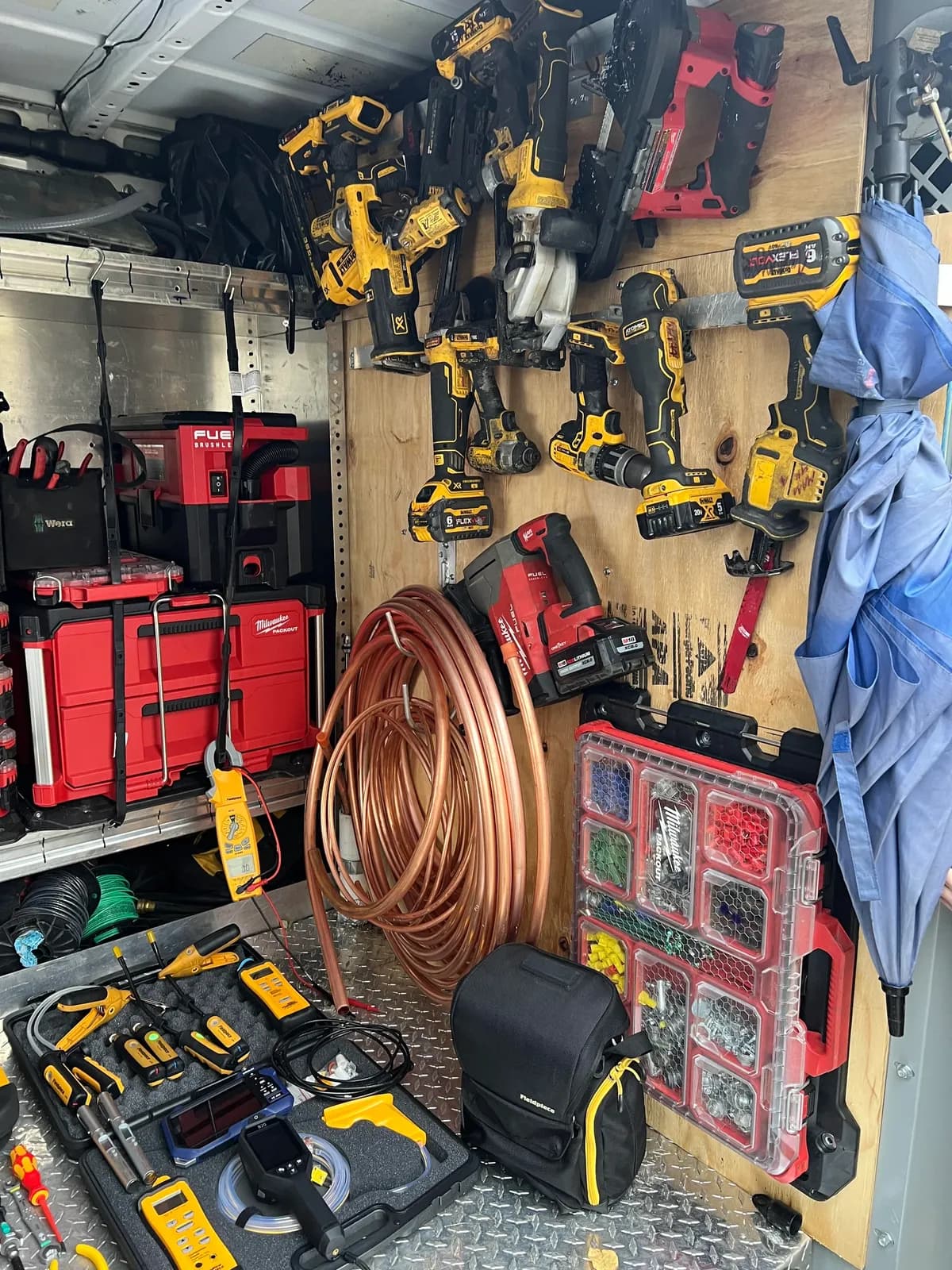 DeWalt cordless drill wall, copper line set, and Milwaukee Packout supply organizers stocked inside the service truck